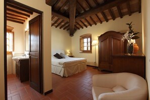 Un dormitorio con cama, mesita de noche, lámpara y un armario de madera.