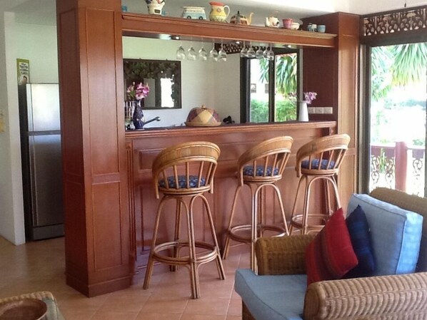 A kitchen with a bar area, three wicker bar stools, a refrigerator, and a sofa with cushions. - Affordable beachside luxury in a beautiful intimate setting. (Ko Samui)