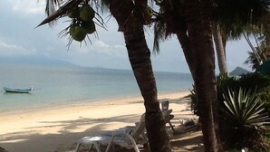 A beach with a boat, palm trees, and lounge chairs. - Affordable beachside luxury in a beautiful intimate setting. (Ko Samui)