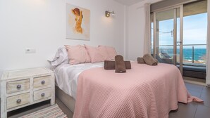 A bedroom with a bed, a nightstand, a painting, and a view of the sea. - MAR COLONIA - Apartment with sea views in Colonia de Sant Jordi. Free WiFi (Ses Salines)