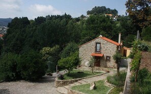A stone house with a red-tiled roof, surrounded by dense greenery and hills. - Quinta da Costeira- AL 1817 Full Rental (Sever do Vouga)