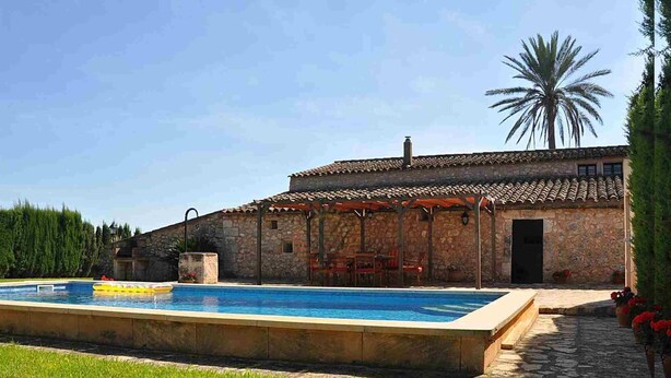 Une piscine avec un mur en pierre et une pergola.
