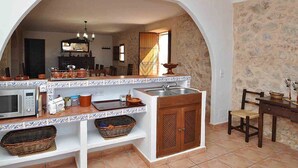 Une cuisine avec une arche, un évier, un four à micro-ondes et un coin repas comprenant une table et des chaises.