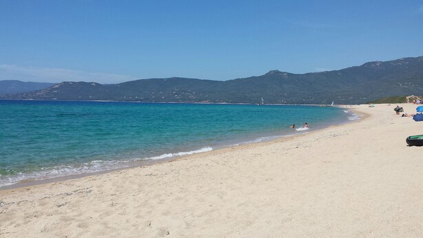 A beach with clear turquoise water, sandy shore, and distant mountains. - Casa Régina - T3 N ° 1 / Ground garden SPACIOUS -  sumptuous sea view (Propriano)