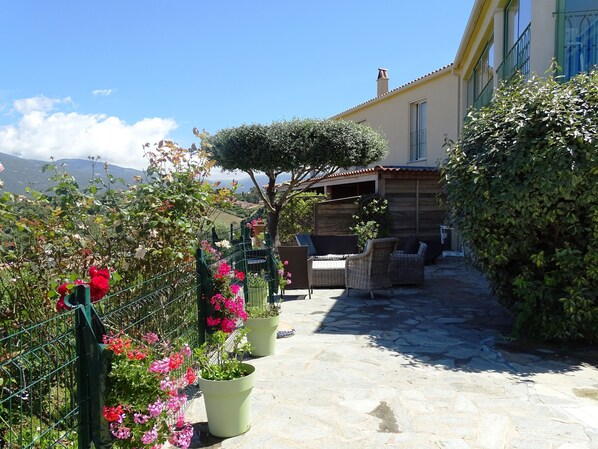 A courtyard with potted plants, outdoor furniture, and a view of the surrounding landscape. - Casa Régina - T3 N ° 1 / Ground garden SPACIOUS - sumptuous sea view (Propriano)