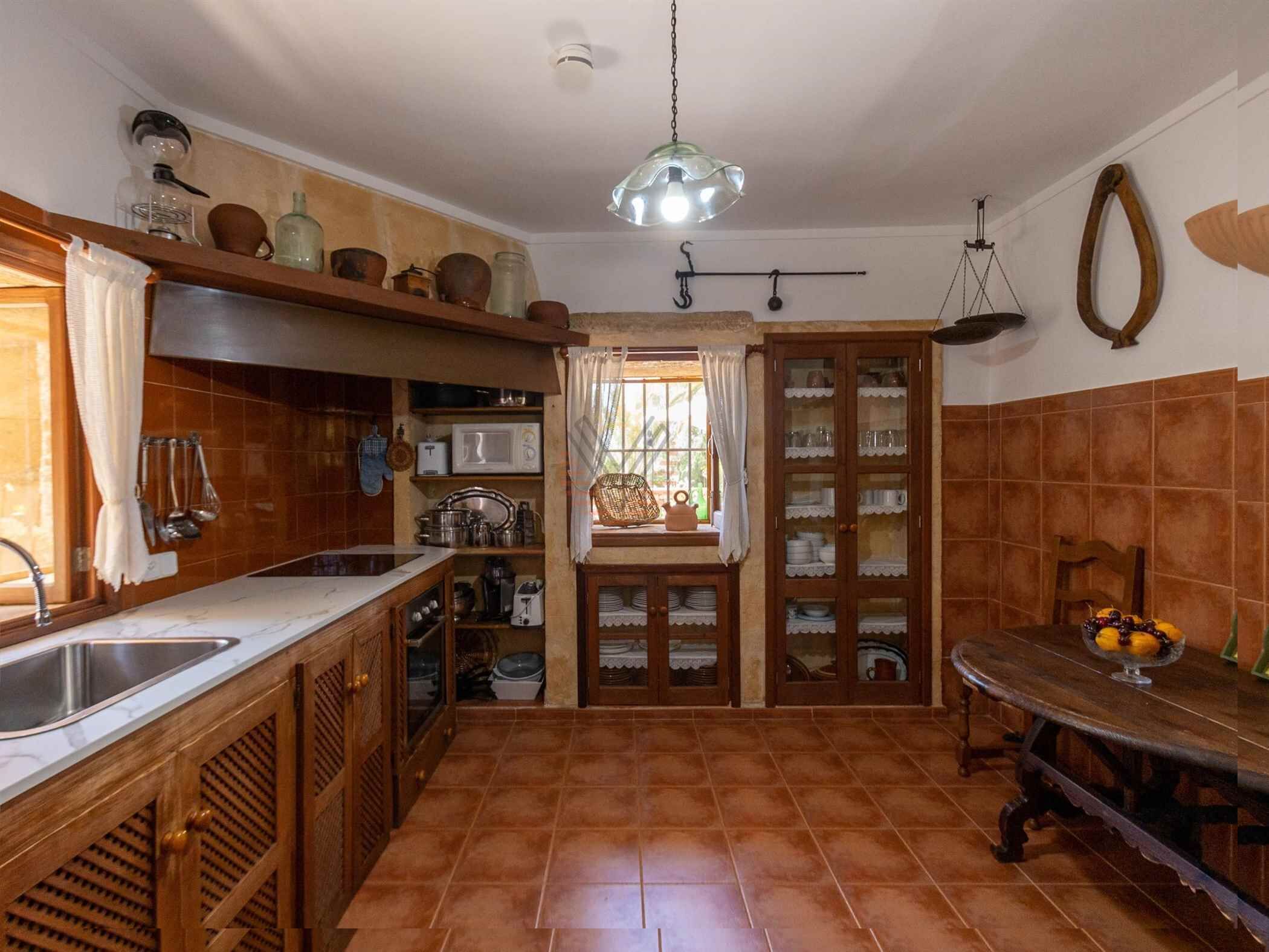 A kitchen with wooden cabinets, a microwave, and a hanging light fixture.