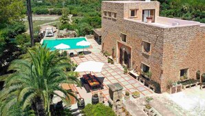 A stone building with a swimming pool, outdoor seating, and palm trees. - Torre Dorada, just 150 metres from Es Morer Vermell beach in Alcudia (Alcudia)