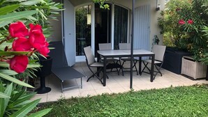 A patio with a table and chairs, surrounded by greenery and a building with a covered area. - Mas de Pont Royal - Golf Estate - Pool & Garden (Mallemort)