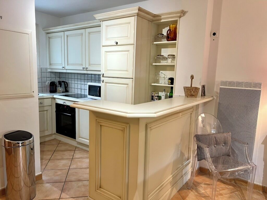 A kitchen with white cabinetry, a countertop, and a trash can.