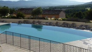 A swimming pool with lounge chairs, surrounded by a fence, and a view of distant mountains. - Mas de Pont Royal - Golf Estate - Pool & Garden (Mallemort)