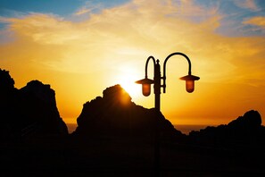 A street lamp silhouetted against a sunset with rocky terrain in the foreground. - Panoramic apartment with fantastic views of the sea (Buggerru)
