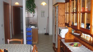 A compact kitchen with a microwave, a sink, and a dining area with a fruit bowl. - Panoramic apartment with fantastic views of the sea (Buggerru)