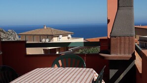 A terrace with a table and chairs, overlooking a coastal view with buildings and the sea. - Panoramic apartment with fantastic views of the sea (Buggerru)