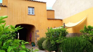 A courtyard with a yellow building, a small window, and a white canopy. - The Ancient House, wonderful Sardinia! (Masainas)