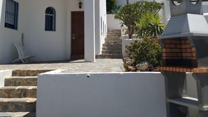A white building with a wooden door and a small porch area. - House and garden, quiet area, near the beach (San Jose)