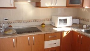 A kitchen with wooden cabinets, a microwave, and a sink. - House and garden, quiet area, near the beach (San Jose)