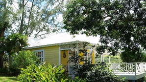A yellow house with a white porch and a small deck.