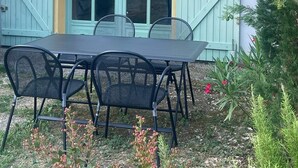 Une terrasse avec une table et des chaises, une porte en bois et un mur bleu.