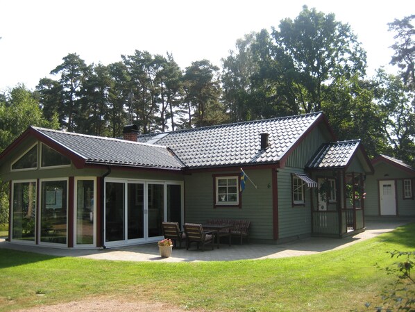 Ein zweistöckiges Haus mit überdachter Veranda, einer Flagge und der Hausnummer 6.