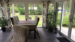 A covered patio with a dining table, chairs, and potted plants. - Lovely cottage in Juleboda a short walk from the fine sandy beach. (Degeberga)