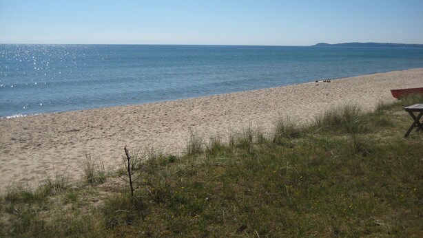 A beach with a clear sky, a sandy shore, and a small red boat. - Lovely cottage in Juleboda a short walk from the fine sandy beach. (Degeberga)