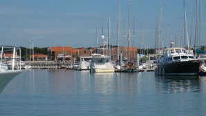 A marina with various boats docked, a building with a red roof, and a clear blue sky.