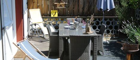 An outdoor patio with wicker furniture, a table set for dining, and a lounge chair.