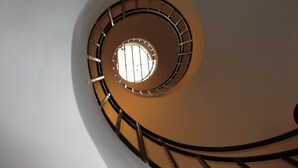 Eine Wendeltreppe mit einem runden Fenster am oberen Ende, umgeben von Metallgeländern.