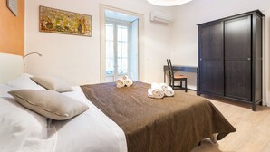 Ein Schlafzimmer mit Bett, Sessel, Kleiderschrank und einem Gemälde an der Wand.