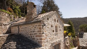 A stone building with a sloped roof, a small window, and a door. - Stunning charming detached house with private heated pool (La Roque-Sainte-Marguerite)