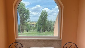 A small room with a table and two chairs, a window with a view of trees and a building, and a tiled floor. - Daniele House - Relaxation and Volcanic Water under the Stars Occasum (Canino)