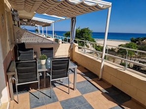 Un balcon avec une table et des chaises, une vue sur la mer et un sol carrelé.