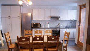 A compact kitchen with white cabinets, a stainless steel refrigerator, a microwave, and a sink. - fantastic location, 3 minutes walk to piste & village - sleeps 8, wifi & views! (RA)