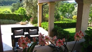 An outdoor patio area with a pergola, a seating arrangement, and a view of a landscaped garden. - Villa with private pool, situated in the heart of the Pollensa countryside (Pollença)