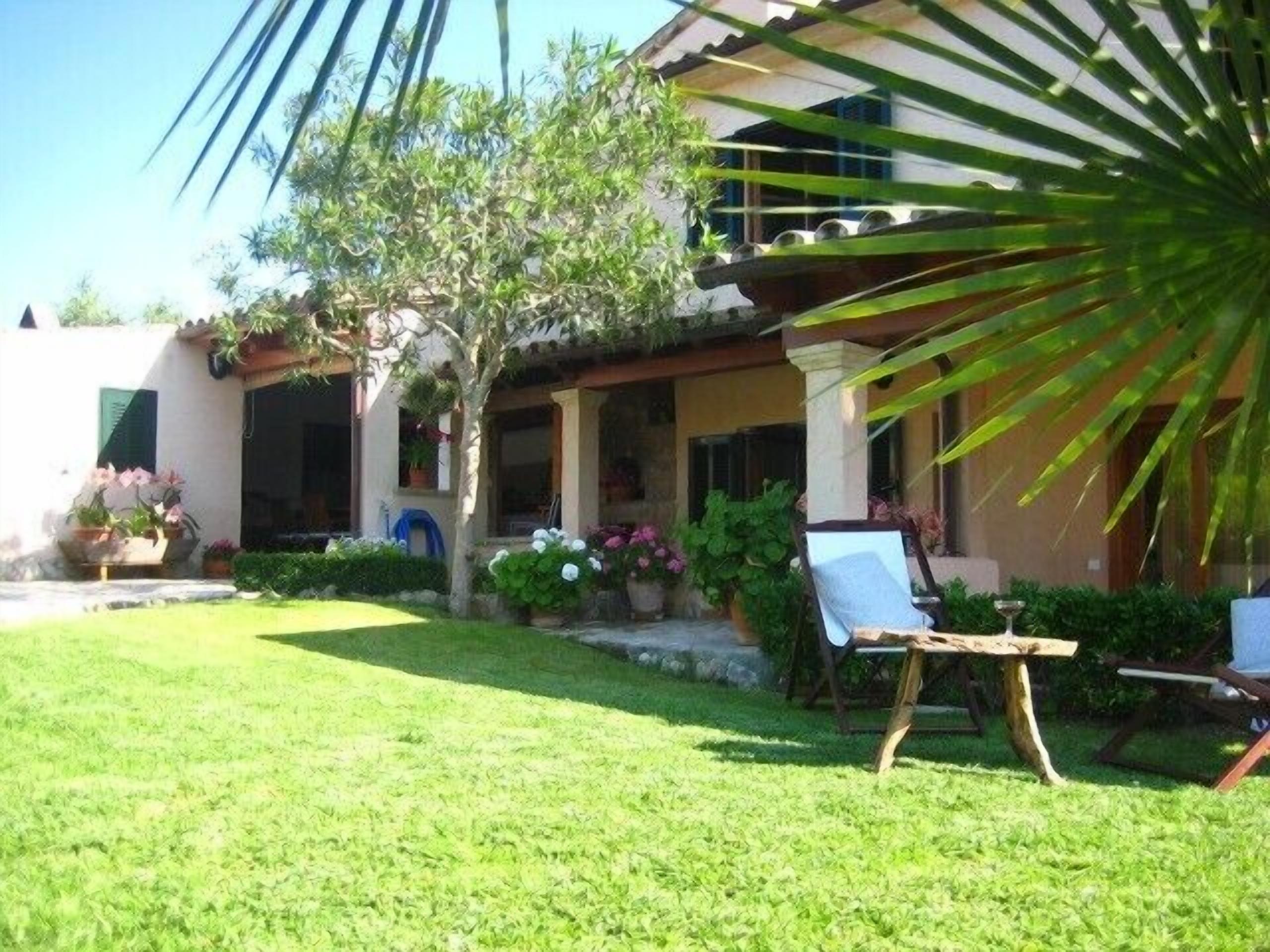 Una casa con un porche cubierto, césped y una silla.