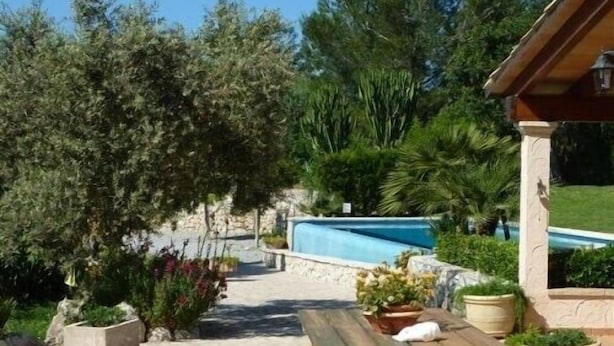 A pool area with a wooden bench and potted plants. - Villa with private pool, situated in the heart of the Pollensa countryside (Pollença)