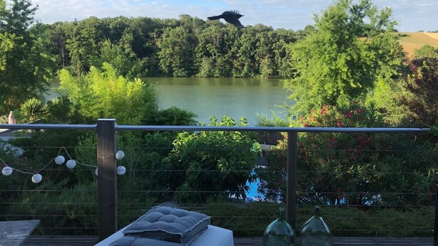 Een terras met uitzicht op een meer, omringd door groen en bomen.