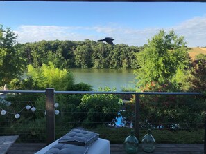 Eine Terrasse mit Blick auf einen See, umgeben von Grünflächen und Bäumen.