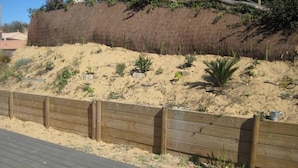 Une zone sablonne avec une clôture en bois et une terrasse en bois.