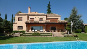 A two-story house with a swimming pool in front.