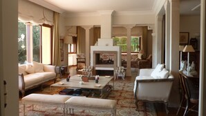 A spacious living room with a fireplace, comfortable seating, and a large window providing natural light.