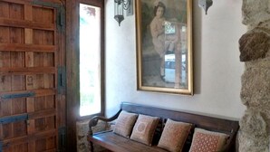 A wooden bench with patterned cushions, a framed picture on the wall, and a rustic wooden door.