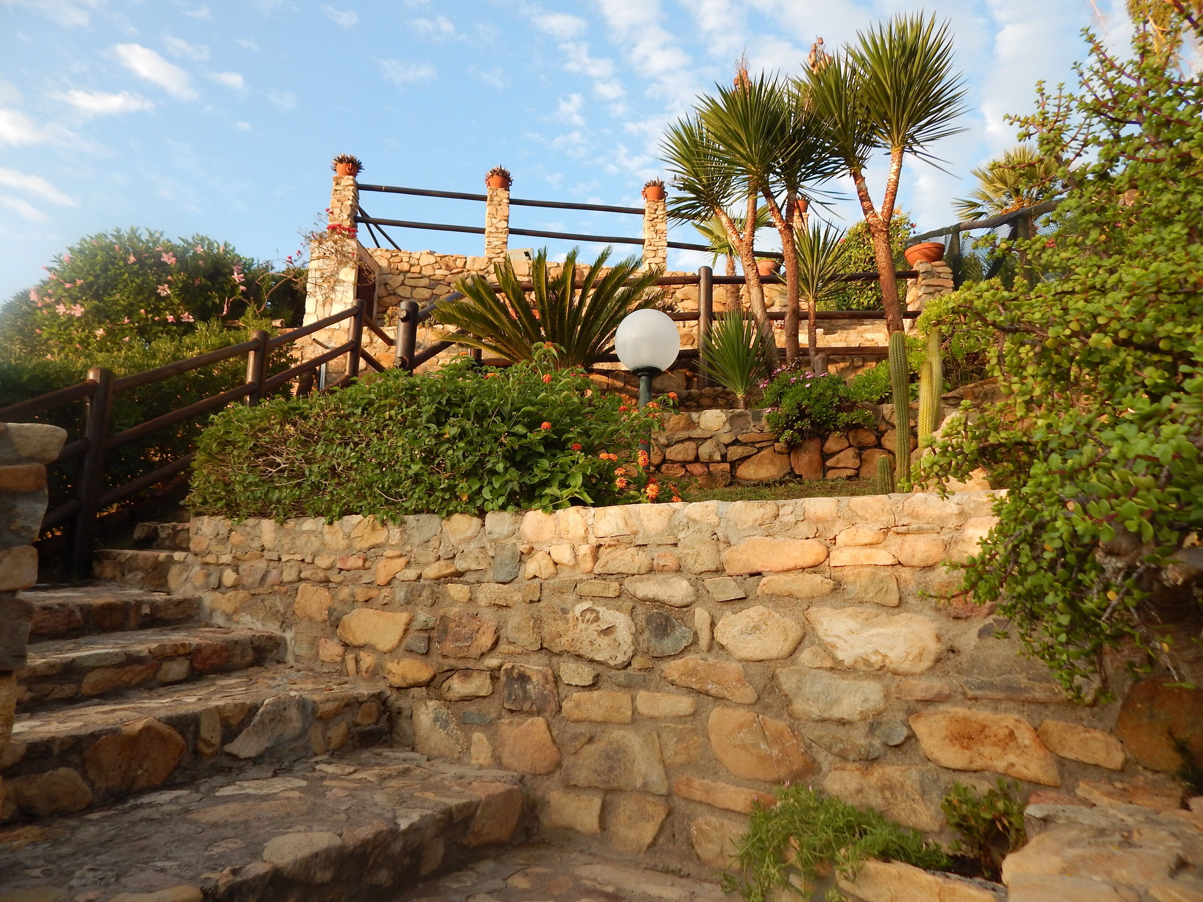 A stone staircase leading up to a stone wall with a wooden railing.
