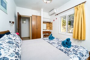 Habitación de hotel con dos camas, un armario de madera, un escritorio y una ventana con cortinas.