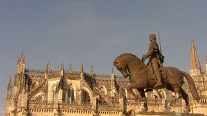 Standing proudly in front of a grand Gothic-style building, a historic statue of a figure on horseback showcases the structure's rich heritage.