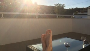 A balcony with a glass table, a wine glass, and a pair of feet. - Beautiful villa for 8 people with private pool close to the beach (São Martinho do Porto)