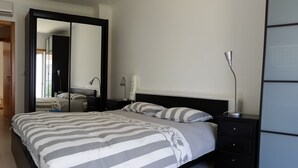 A modern bedroom with a large bed, a nightstand, a lamp, and a mirror. - Beautiful villa for 8 people with private pool close to the beach (São Martinho do Porto)