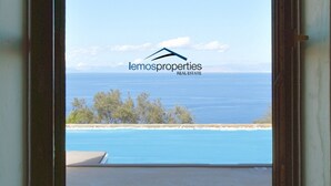 A view through a window of a property with a logo 'lemosproperties' and a beach with trees in the background.