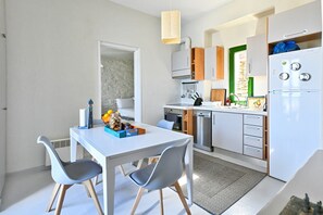 A compact kitchen with a dining area, featuring a white table, grey chairs, and modern appliances. - Villa Eliza with a swimming pool and a sea view (Kea)