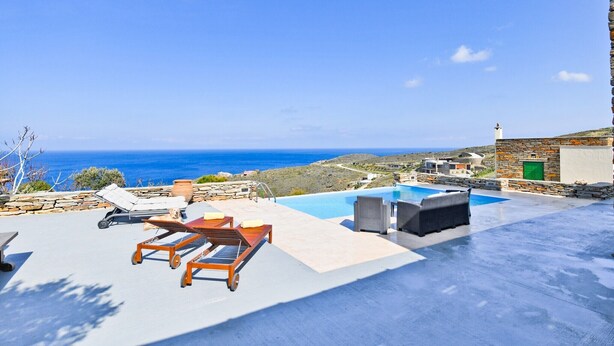 A rooftop pool area with lounge chairs and a view of the sea.